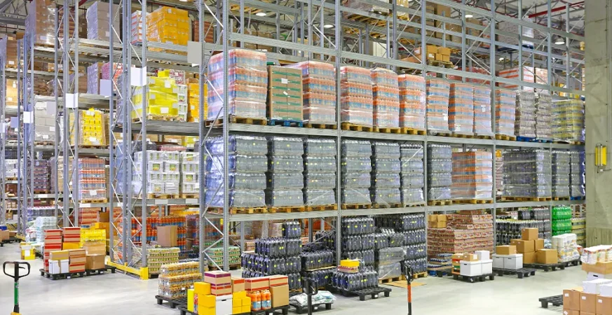 Vista aérea de armazém com corredores estreitos e empilhadeiras operando, ilustrando como o layout influencia na escolha do equipamento ideal.