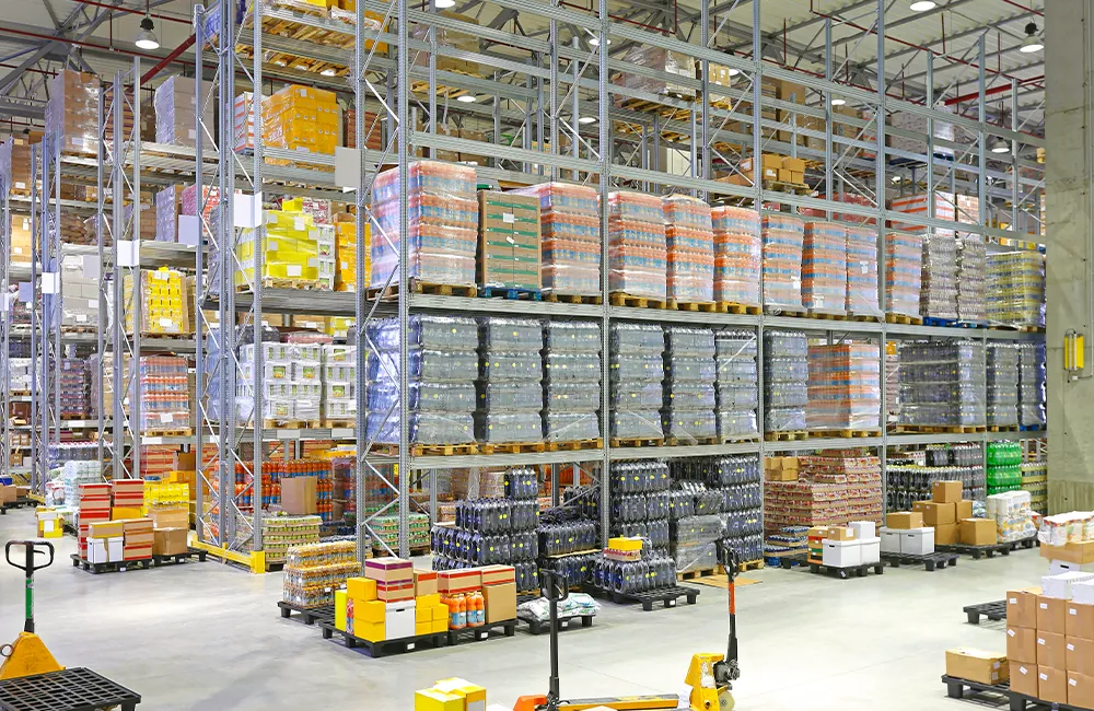 Vista aérea de armazém com corredores estreitos e empilhadeiras operando, ilustrando como o layout influencia na escolha do equipamento ideal.