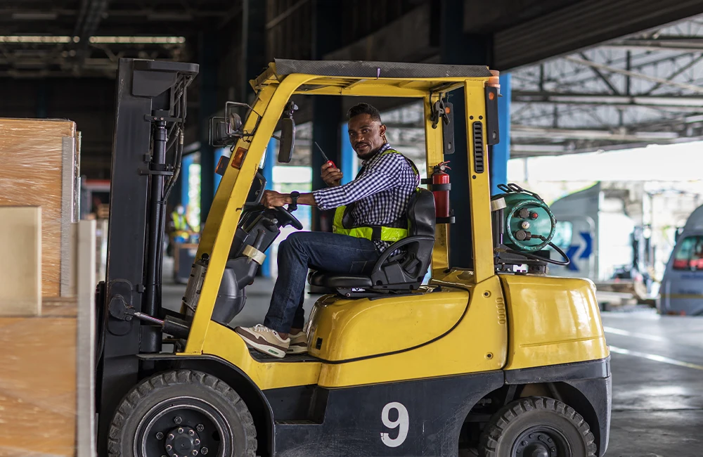 Operador conduzindo empilhadeira em ambiente industrial durante atividade logística.
