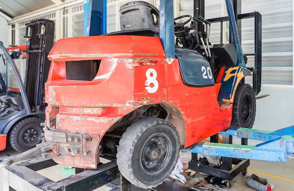 Empilhadeira em processo de manutenção dentro de uma oficina industrial. Crédito: © navintar / Adobe Stock