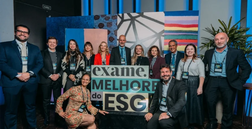 Equipe corporativa reunida em evento de premiação ESG da Exame, posando em frente ao painel "Melhores do ESG".