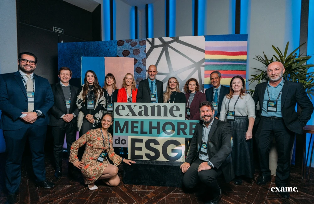 Equipe corporativa reunida em evento de premiação ESG da Exame, posando em frente ao painel "Melhores do ESG".