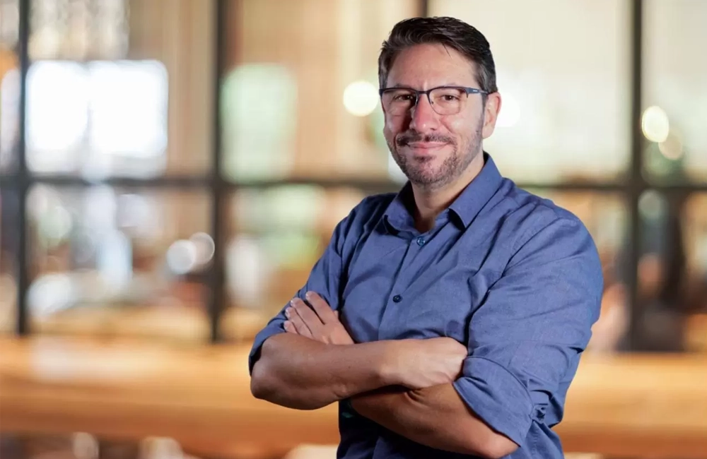 Retrato profissional de um executivo do setor logístico posando com os braços cruzados.