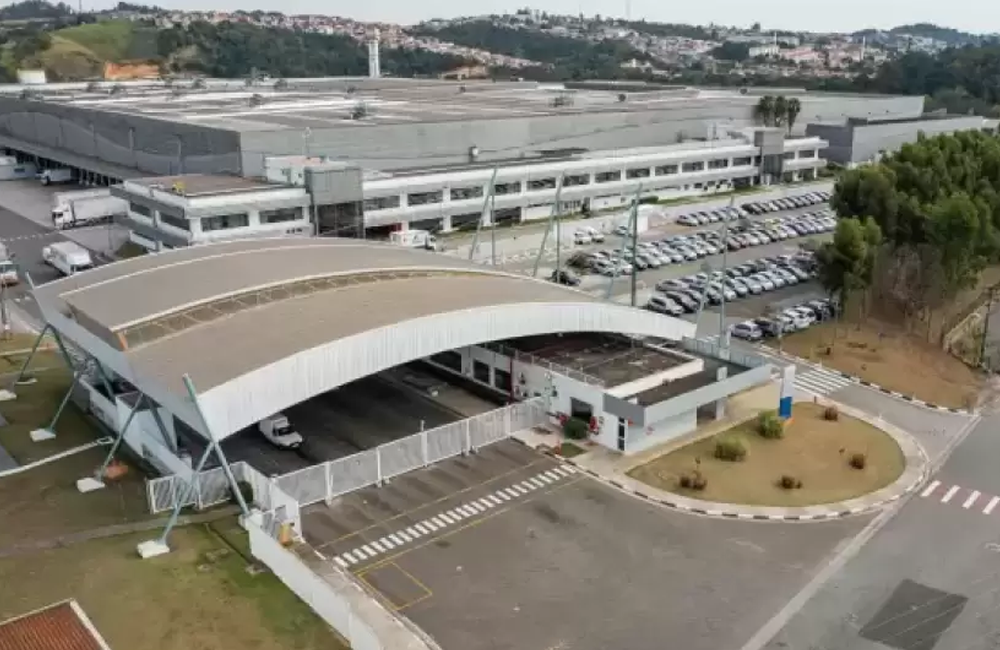 Vista aérea de um centro logístico de grande porte com área de expedição e estacionamento operacional.