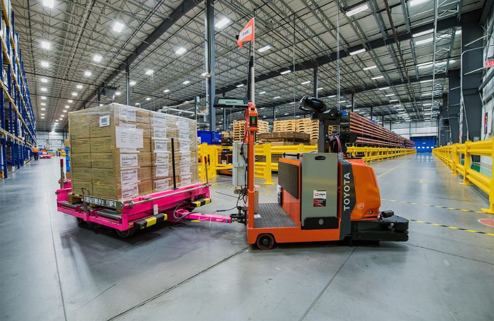 Robô móvel autônomo (AMR) transportando paletes em corredor de armazém, ilustrando a automação progressiva e a otimização do fluxo interno em CDs.