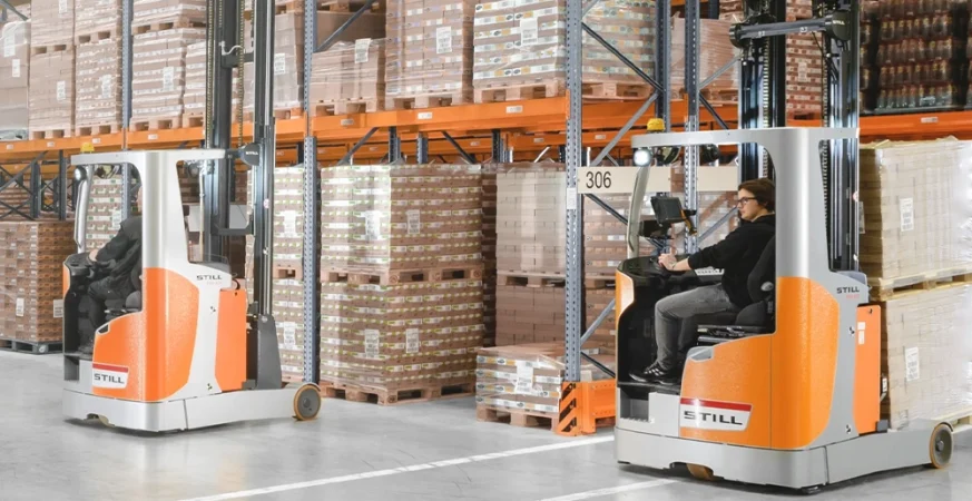 Empilhadeira retrátil operando em corredor estreito de um centro de distribuição com racks altos e movimentação vertical.