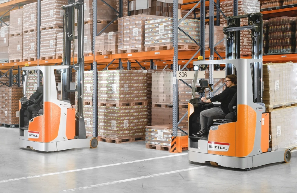 Empilhadeira retrátil operando em corredor estreito de um centro de distribuição com racks altos e movimentação vertical.