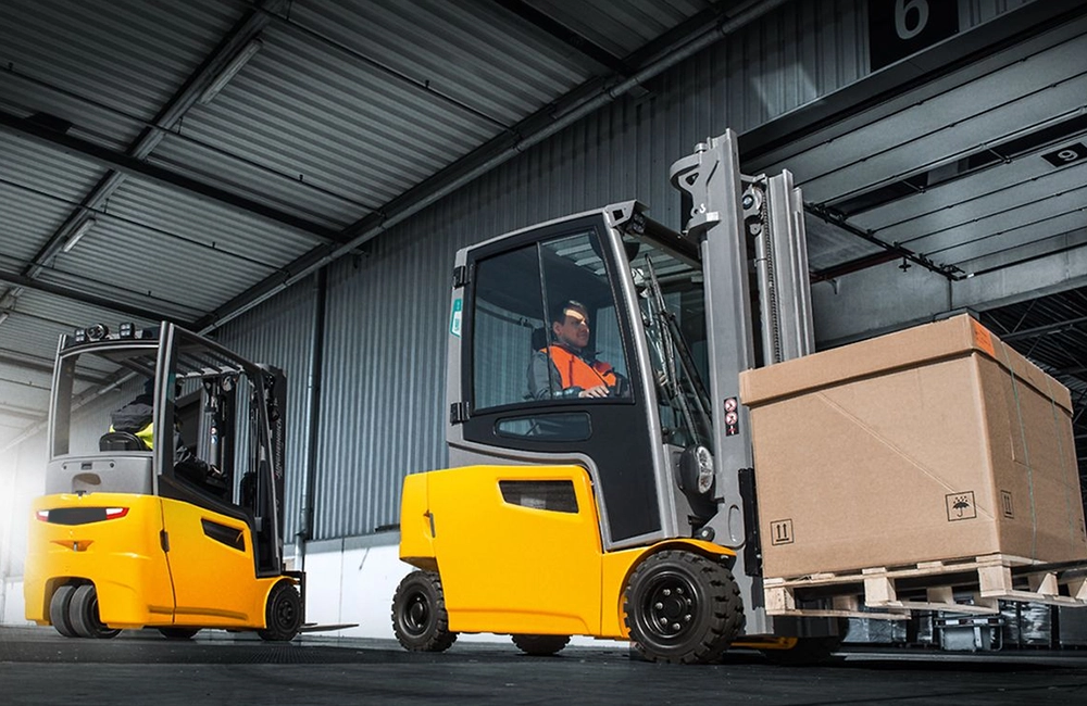 Empilhadeiras elétricas operando em galpão logístico moderno com corredores altos e operação indoor.