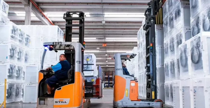 Operação logística com empilhadeiras retráteis movimentando cargas em armazém, ilustrando preparação de estoque para alta demanda.