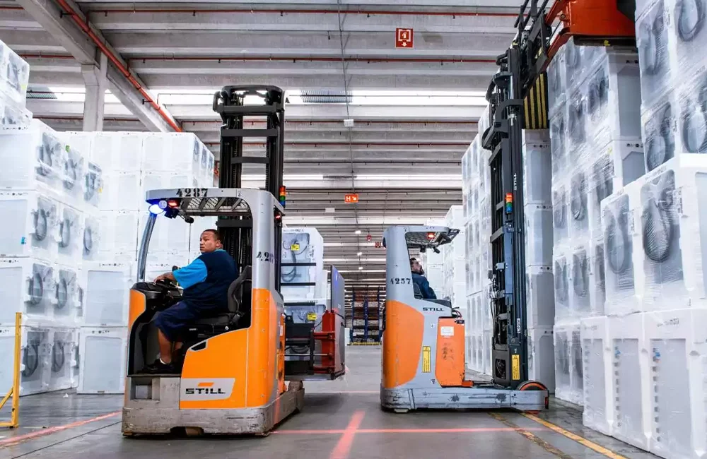 Operação logística com empilhadeiras retráteis movimentando cargas em armazém, ilustrando preparação de estoque para alta demanda.