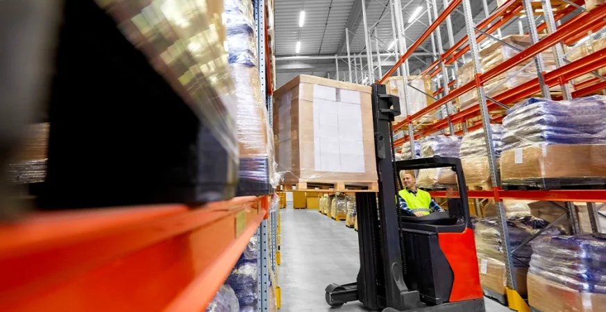 Empilhadeira operando em corredor de armazém logístico no Brasil, ilustrando eficiência e redução de custos com locação de empilhadeiras.