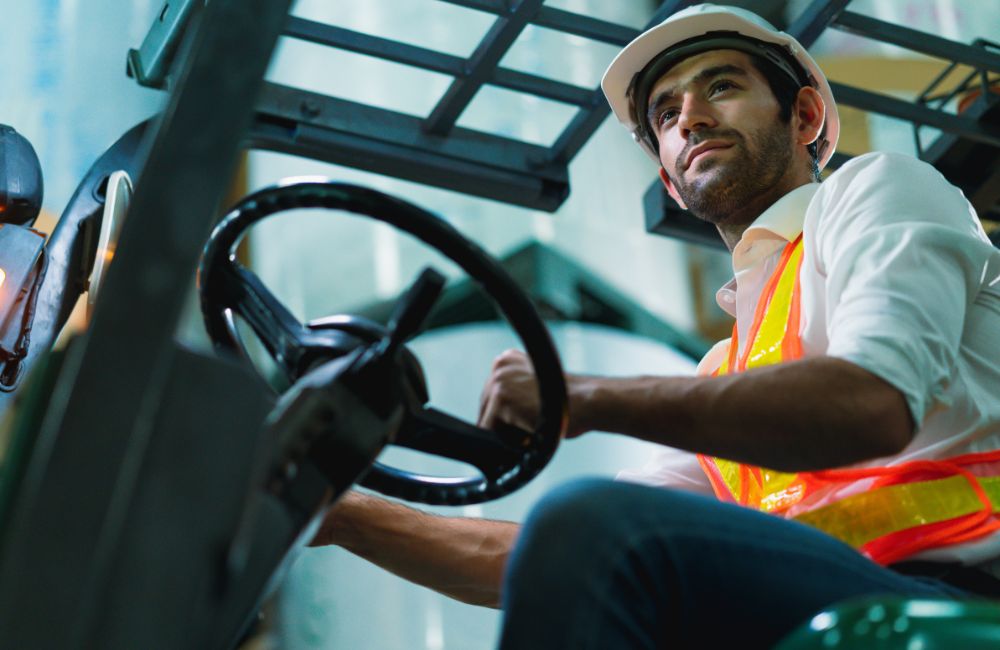 Operador de empilhadeira em armazém logístico demonstrando postura sentada correta, ilustrando os requisitos de ergonomia e assentos da norma NR-17 na intralogística.