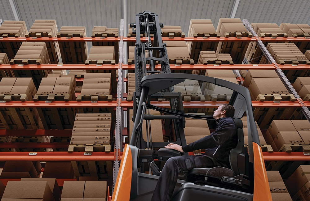 Empilhadeiras operando em dois turnos dentro de um centro de distribuição, mostrando aumento de fluxo e desgaste operacional.