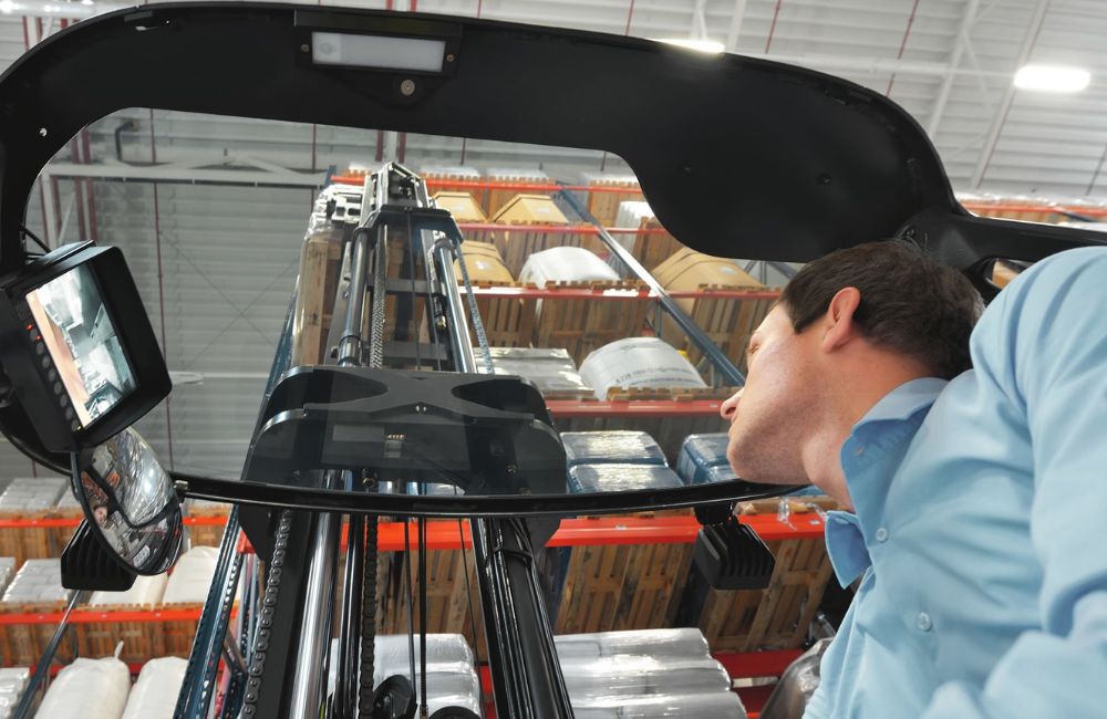 Texto Alternativo (Alt Text):Técnicos avaliando um mastro de empilhadeira, ilustrando a análise de engenharia para escolher entre retrátil e contrabalançada interna, considerando a robustez e a estabilidade.