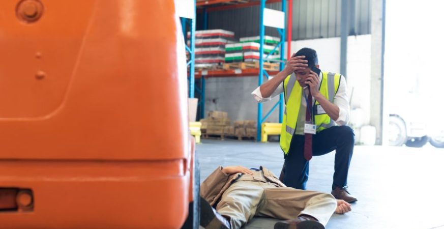 Empilhadeira parada ao lado de materiais caídos no chão, ilustrando riscos de acidentes em operações logísticas.